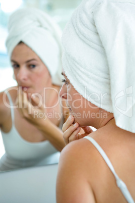 woman wearing a hair toowel inspecting her complexion