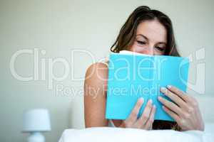 smiling woman reading a book in bed