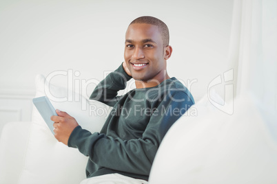 Smiling man using tablet on the sofa