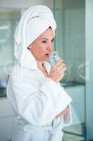 woman wearing a dressing gown drinking a glass of water