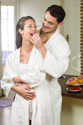 Man feeding strawberry to woman