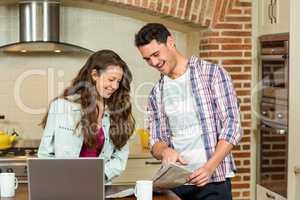 Happy couple reading newspaper in kitchen