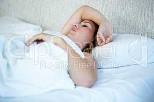 Blonde woman asleep in a white bed