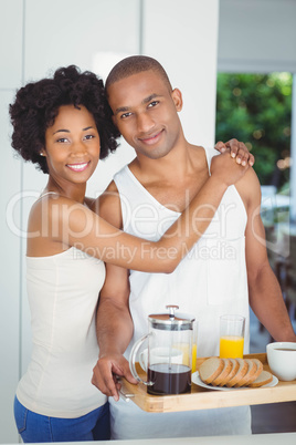 Happy couple holding breakfast tray in the kitchen