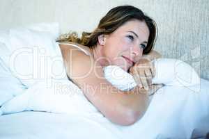 smiling woman lying in her bed , daydreaming