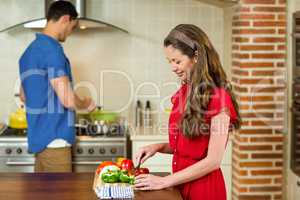 Woman chopping vegetables and man cooking on stove