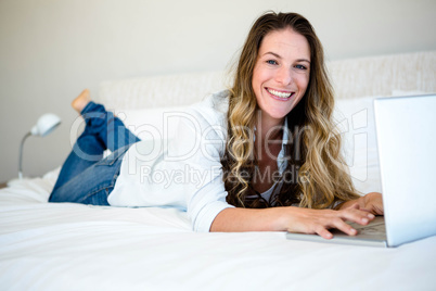 woman lying on her bed on her laptop