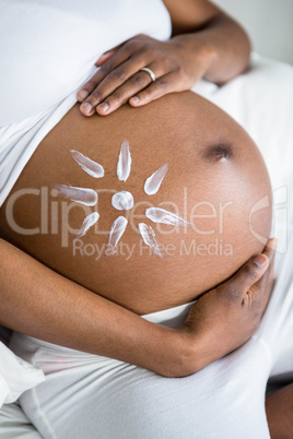 Pregnant woman applying cream on her belly