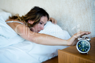 woman reaching to turn off her alarm clock