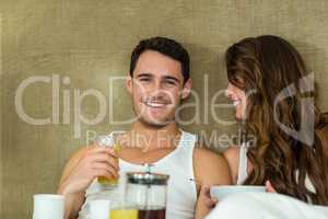 Young couple having breakfast on bed