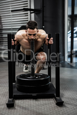 Shirtless man pushing heavy weights
