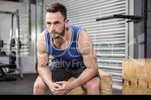 Muscular man sitting on wooden block