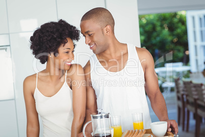 Happy couple holding breakfast tray in the kitchen