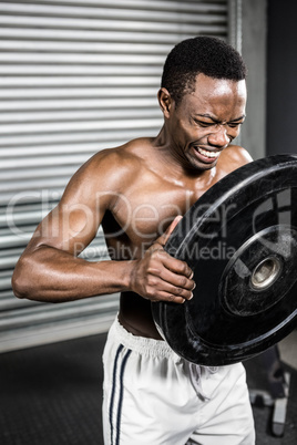 Shirtless man holding heavy weight