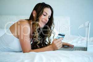 smiling woman holding her laptop and credit card