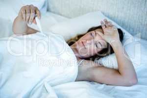 sick woman in bed reading a thermometer