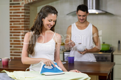 Woman ironing a shirt in kitchen