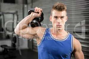 Muscular man lifting heavy kettlebell