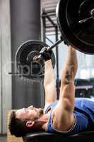 Muscular man on bench lifting barbell