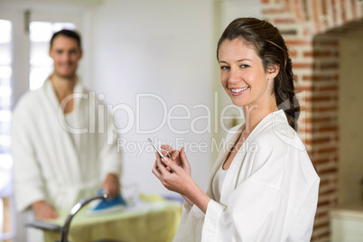 Beautiful woman in bathrobe typing a text message on smartphone