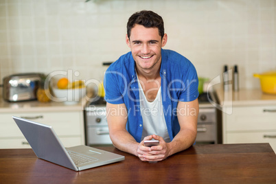 young man leaning on kitchen worktop