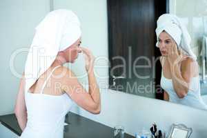 woman is applying face cream in the mirror