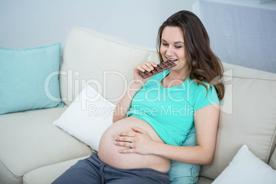 Smiling pregnant woman eating chocolate