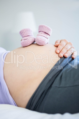 Pregnant woman with baby shoes on belly