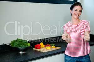 smiling woman preparing vegetables for dinner and giving a thumb