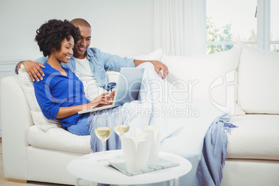 Happy couple on the sofa using laptop