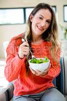 smiling woman eating a bowl of salad
