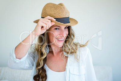 woman wearing a straw fedora smiling and looking away