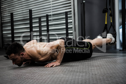 Shirtless man doing push up with the rope