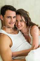 Portrait of young couple cuddling on bed
