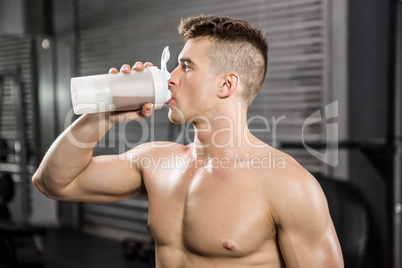 Shirtless man on bench drinking protein shake