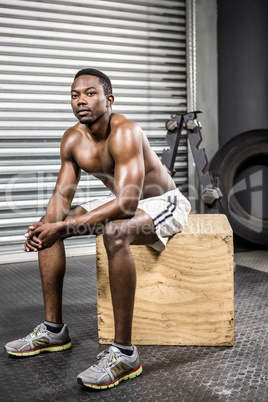 Shirtless man sitting on wooden block