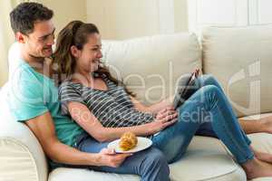 Young couple reading newspaper on sofa