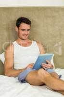 Young man using digital tablet in bedroom