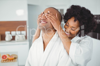 Smiling woman hiding the eyes of her husband