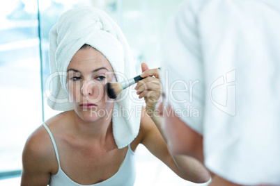 woman applying face powder in the bathroom mirror