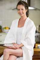 Beautiful woman in bathrobe sitting with smartphone