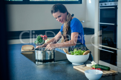 smiling woman cooking on the stove top