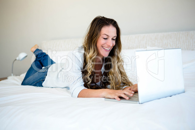 woman lying on her bed on her laptop