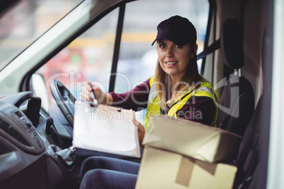 Delivery woman holding clipboard to camera