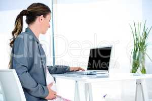 pregnantbusiness  woman typing on her laptop