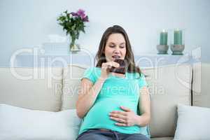 Smiling pregnant woman eating chocolate