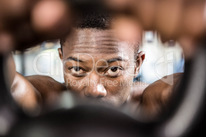 Shirtless man lifting heavy kettlebell