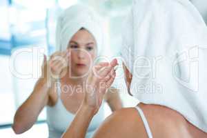 woman applying face cream in the mirror