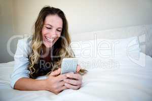 woman lying on her bed on her mobile phone