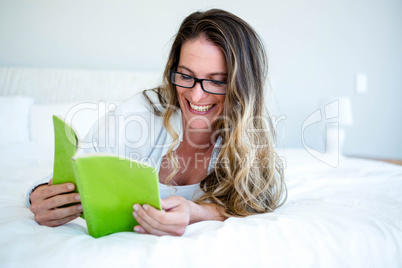 smiling woman lying on her bed reading